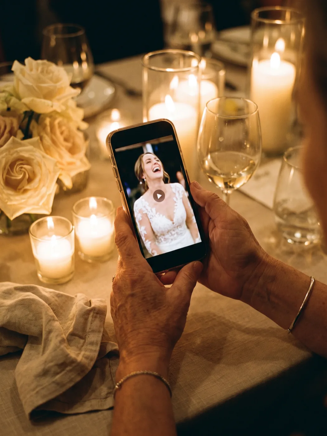 Hands holding a phone playing the bride's video message at the wedding table