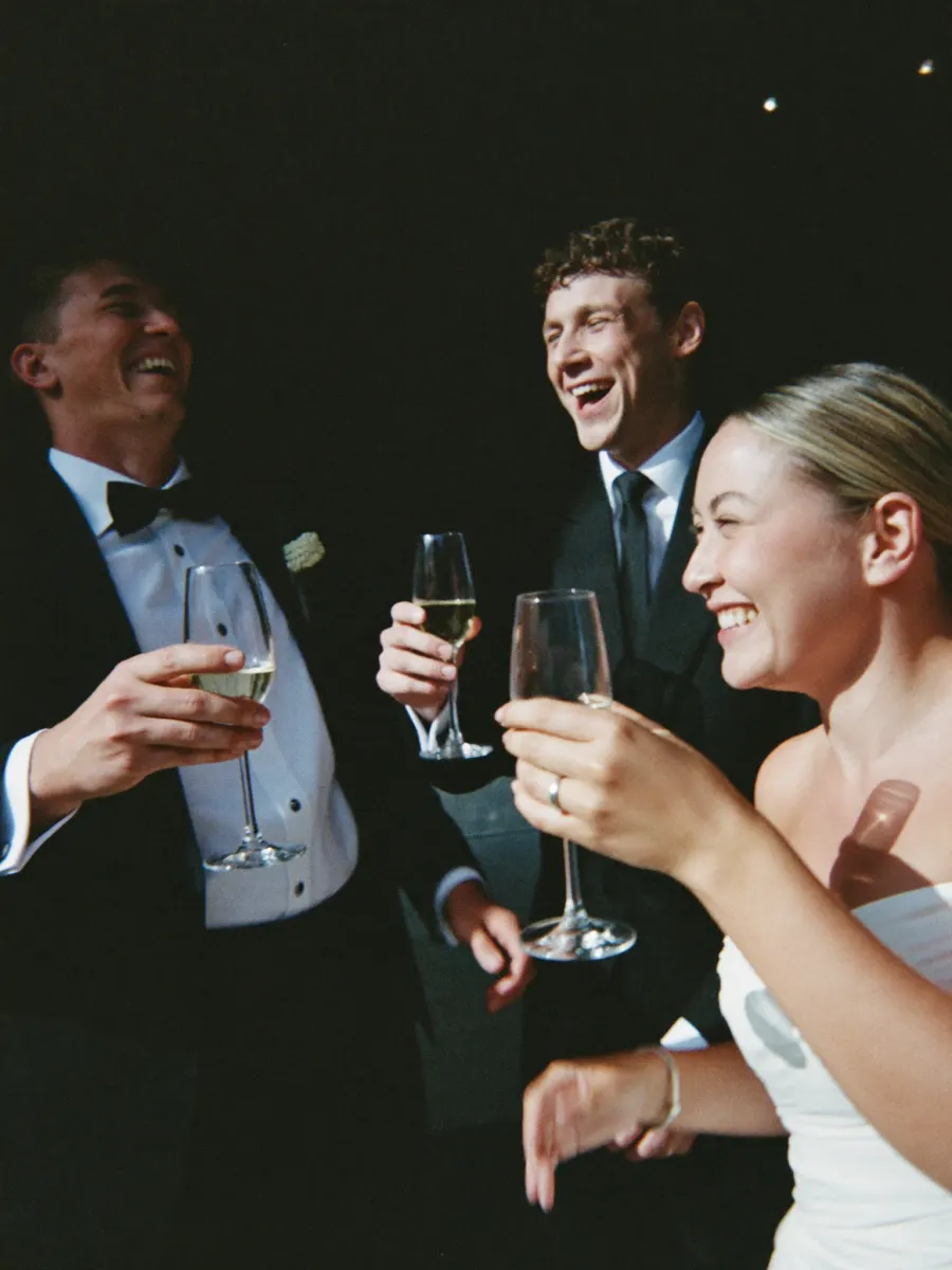 Hochzeitsgäste lachen und stoßen mit Sektgläsern an