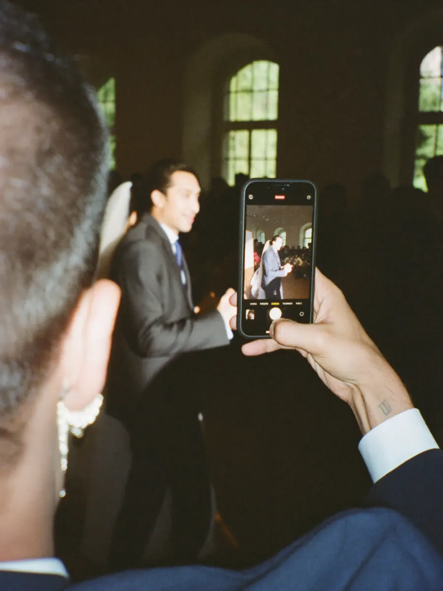 Hochzeitsgast fotografiert das Brautpaar mit dem Smartphone